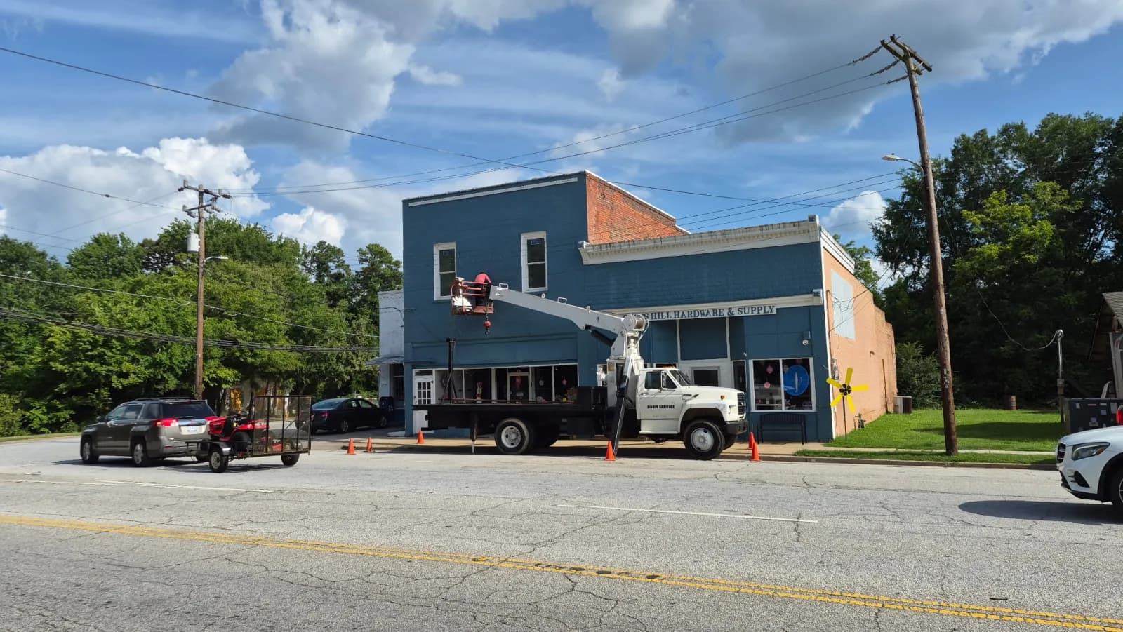 Boom truck with man-basket raised working on a downtown storefront sign