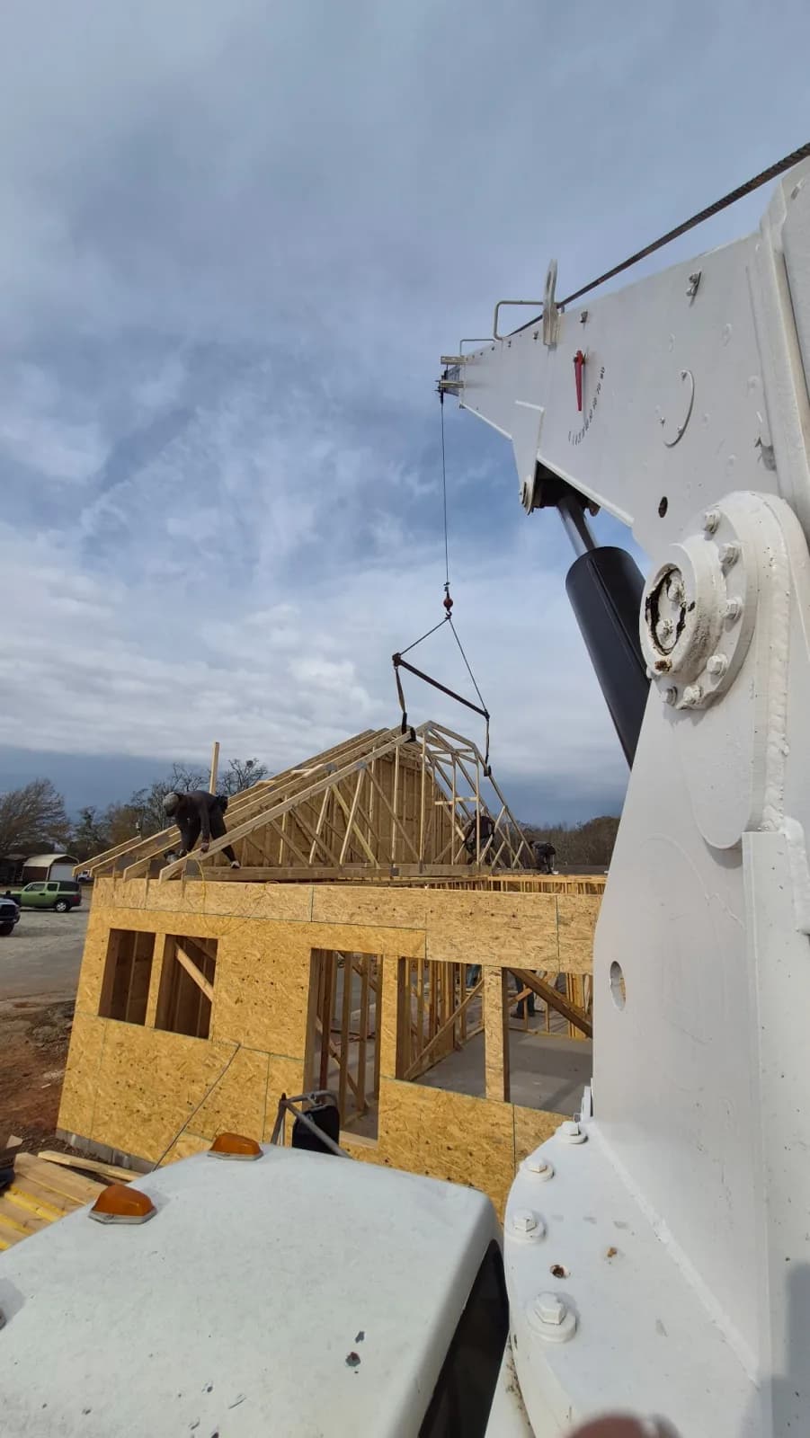 Boom truck lifting a wide-span roof truss